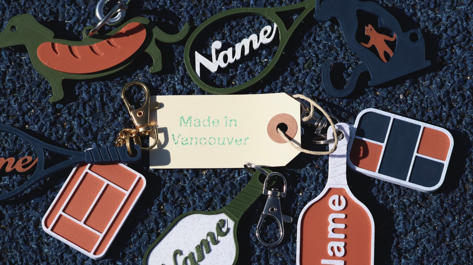 A flat lay of Mynnë personalized tennis and pickleball court charms and keychains on a dark textured surface